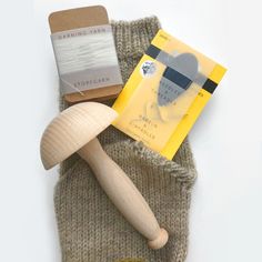 a knitted mitt with a wooden spoon, book and other items on it