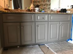 a bathroom vanity is being painted in gray with blue tape on the floor and walls