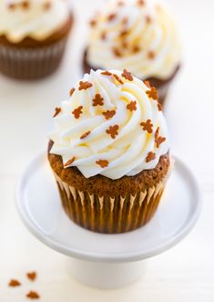 three cupcakes with white frosting and sprinkles on a plate