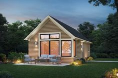 a small house is lit up at night with lights on the windows and patio furniture