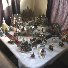 a table topped with lots of small christmas village figurines