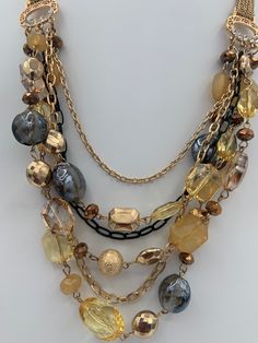 "Beautiful elegant multilayered necklace.  Lobster claw closure. Shortest layer is 23 \", longest 28\", extension 3\".  Six layers , 3 with beads and three without, only chains.  Beads include crystals, glass beads, foiled beads, acrylic beads.  Chains are one black and two gold tone. Connectors have clear rhinestones.  Weight 3.5 oz." Metal Layered Necklace With Beaded Chain For Party, Costume Jewelry Metal Layered Necklace For Party, Party Costume Jewelry Layered Necklace In Metal, Gold Multi-strand Beaded Necklaces With Faceted Beads, Gold Layered Bohemian Beaded Necklaces, Bohemian Gold Layered Beaded Necklaces, Gold Multi-strand Jewelry For Party, Bohemian Gold Layered Necklaces, Layered Double Strand Necklace For Party