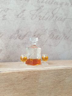 two glasses sitting on top of a wooden table next to a bottle of alcohol and a glass