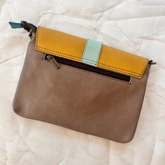 The saddle bag is sure to become your favorite companion while out and about, whether running arrands, sight-seeing, or dancing the night away! This wristlet is perfectly sized to carry your essentials and can be carried as a wristlet, used as a clutch, or attach the included adjustable leather strap and wear it as a crossbody. Saddle has a main zippered compartment that is covered by a colorful magnetic flap. Inside is a zip pocket and the the back has another zip pocket for easy access. 10" L x 7" H x 1.25" W Strap: Adjustable up to 50" Wristlet: 7.5" Long View entire Soruka collection This is a one-of-a-kind piece created, designed, and manufactured by hand using discarded, leftover, or no longer in use leather, in order to reduce the ecological impact of leather production. Versatile Adjustable Shoulder Bag For On-the-go, Trendy Brown Leather Pouch, On-the-go Crossbody Clutch With Detachable Strap, Adjustable Crossbody Bags For On-the-go, Versatile Clutch With Detachable Strap For Daily Use, Yellow Shoulder Bag With Cell Phone Pocket For On-the-go, Brown Shoulder Bag Pouch With Adjustable Strap, Clutch Phone Bag With Detachable Strap, Trendy Brown Pouch With Adjustable Strap