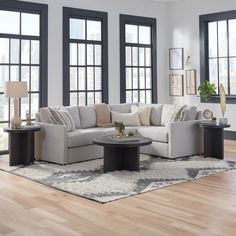 a living room with two couches and a coffee table in front of three windows