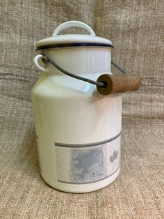 a white jug with a wooden handle sitting on top of a brown cloth covered couch