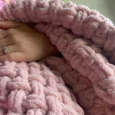 a woman's hand under a pink blanket with a diamond ring on her finger