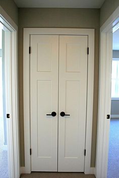 an empty room with two white doors and carpeted flooring in front of it