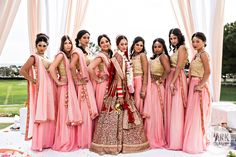 a group of women standing next to each other in front of a white and pink backdrop