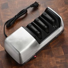 a silver and black battery charger sitting on top of a wooden table