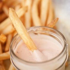 a glass jar filled with liquid next to french fries