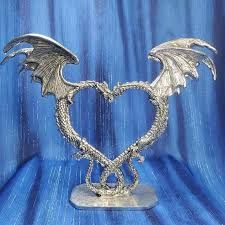 a silver dragon sculpture sitting on top of a blue table next to a black background