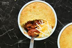 two white bowls filled with food on top of a black table next to each other