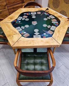 a wooden table topped with lots of cards on top of a green leather chair next to a dresser