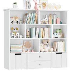 a white bookcase filled with lots of books next to a teddy bear and other toys