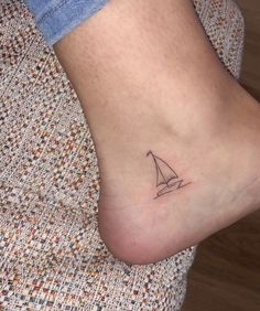 a small sailboat tattoo on the foot of a woman's left leg,