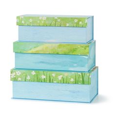 three blue boxes with flowers painted on the sides and grass growing out of each box