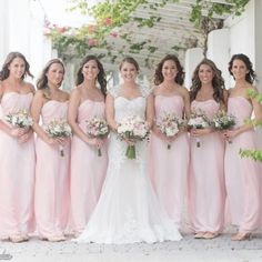 a group of women standing next to each other wearing pink bridesmaid gowns