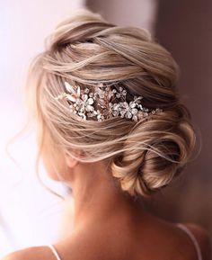 a woman wearing a bridal hair comb with flowers on it's head, looking off to the side