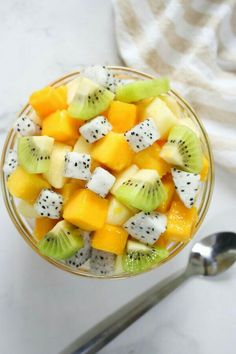 a fruit salad in a bowl with kiwi, oranges and melon slices