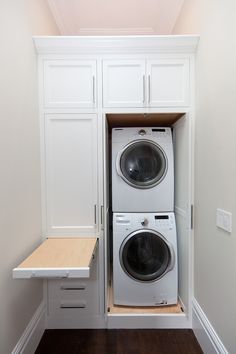 a white washer and dryer in a small room with built - in cabinets