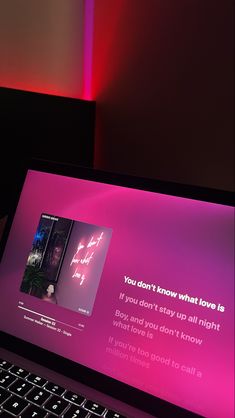 an open laptop computer sitting on top of a desk next to a red light filled wall