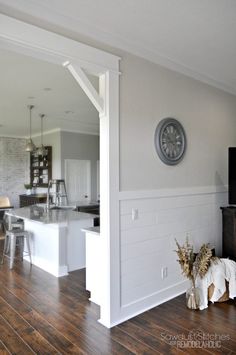 an open living room and kitchen area with wood flooring, white walls and wooden floors