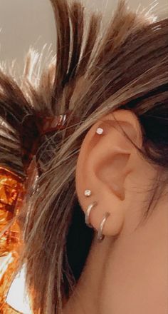 a close up of a person's ear with two piercings on top of it