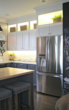 a modern kitchen with stainless steel appliances and white cabinets, along with an island in the middle