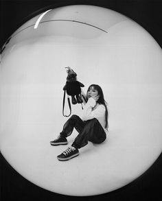 a woman sitting on the ground with a stuffed animal in front of her and a black cat