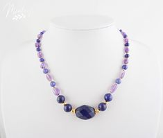 Stunningly elegant necklace made of beautifully complementing delicate purple amethysts and blue sapphires alternating with blue lapis lazuli and dark blue sapphires. Perfectly integrated in color are 4 large blue lapis lazuli gemstones and a 20mm blue sapphire in the center of the necklace. All gemstones are embedded in 18K real gold plated elements to nobly round off the combination of gemstones. Matching earrings/necklace are also available upon request so you can wear it as one ensamble. Ple Elegant Blue Amethyst Jewelry, Elegant Sapphire Crystal Necklaces With Round Beads, Elegant Sapphire Round Beads Crystal Necklace, Elegant Sapphire Crystal Necklace With Gemstone Beads, Blue Faceted Amethyst Jewelry, Faceted Blue Amethyst Jewelry, Elegant Tanzanite Gemstone Bead Necklaces, Elegant Tanzanite Gemstone Bead Necklace, Elegant Lapis Lazuli Crystal Necklace With Gemstone Beads