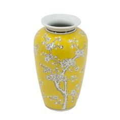 a yellow vase with white flowers painted on the front and bottom, sitting against a white background