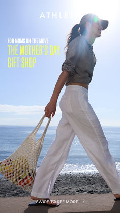 a woman walking on the beach with a bag