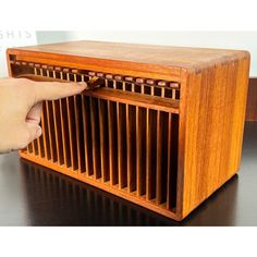 an old wooden radio sitting on top of a black table next to a person's hand