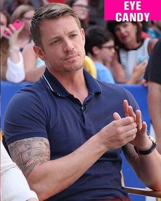 a man sitting in front of a crowd with his hand up to his chest and the words eye candy on it