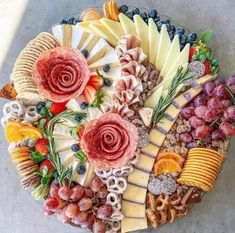 a platter filled with different types of cheeses and meats on top of each other