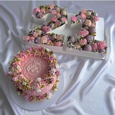 a cake with pink frosting and flowers on it sitting next to the number 50