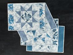 two blue and white quilts sitting on top of a black table next to each other