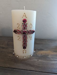 a white candle with a red cross on it