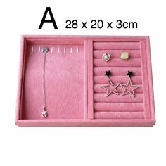 a pink jewelry box with three star charms and two earring sets in it's display case