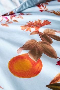 an orange and red flowered design on a white sheet