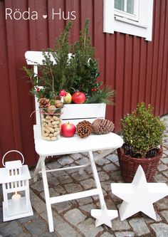 a white table topped with christmas decorations next to a red building