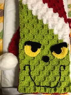 a crocheted green monster with big eyes and santa's hat on it