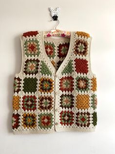 a crocheted vest hanging on a wall