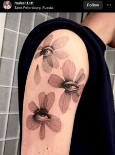 a person with a tattoo on their arm that has flowers and an eye in the middle