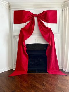 a red curtain draped over a fireplace in a room with wood floors and white walls