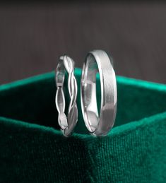 two wedding rings sitting on top of a green velvet box