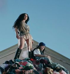 two women standing on top of a pile of clothes