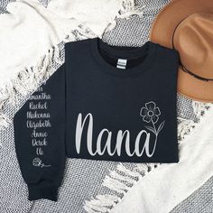 Personalize this Custom Floral Nana Sweatshirt with grandkids names on the sleeve to give her one of the most special Nana Gifts she's ever received! PERSONALIZATION ▸ Please enter the grandchildren's names in personalization box in the order you would like them on sleeve. (For multiple names, please list commas between them) Ex. Adelyn, Makenna, Titus ▸ The Nana design will be automatically added. IMPORTANT NOTES ▸ Unisex Adult Sizing ▸ Rolled Sleeves in pictures is for styling purposes only ▸ Props used In photos are NOT included with purchase GILDAN BRAND SHIRTS ▸ Medium-heavy fabric blend of 50% cotton & 50% polyester (8.0 oz/yd); Fabric blends: Heather Sport colors - 60% polyester, 40% cotton ▸ This sweatshirt feels cozy and is the perfect choice for those colder months. PRINT ▸ This Nana Sweatshirt Ideas, Long Sleeve Tops With Name Print For Family, Personalized Long Sleeve T-shirt, Nana Shirts Ideas, Nana Sweatshirt, Nana Shirts, Kids Names, Nana Gifts, Brand Shirts