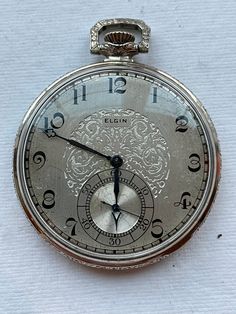 Very Nice Elgin 12 sz Pocket Watch. It has a  Clean Grade 479  Model 4  17 Jewel   Adjusted Movement . The crystal is excellent . It  has a single sunk metal silvered disl with a fancy etched center. The case is a Wadsworth Elgin Streamline and is 14K White Gold Filled . The movement is clean and shiny. It is stem wind/ stem set . It winds easy, sets properly and keeps time.The run quantity is 2000 and  Production date is 1925. A sweet Elgin 12 sz Grade 479 Pocket watc . International buyers please message me for a shipping quote. Thank you Timeless Silver Diamond Watch With Chronometer, Elegant Silver Pocket Watch With Subdials, Silver Diamond Watch With Chronometer For Formal Occasions, Collectible White Gold Round Watch, Classic Engraved Silver Watch Accessories, Silver Timeless Pocket Watch For Anniversary, Timeless Silver Pocket Watch For Anniversary, Antique Silver Diamond Watch With Polished Finish, Antique Engraved Silver Jewelry And Watches